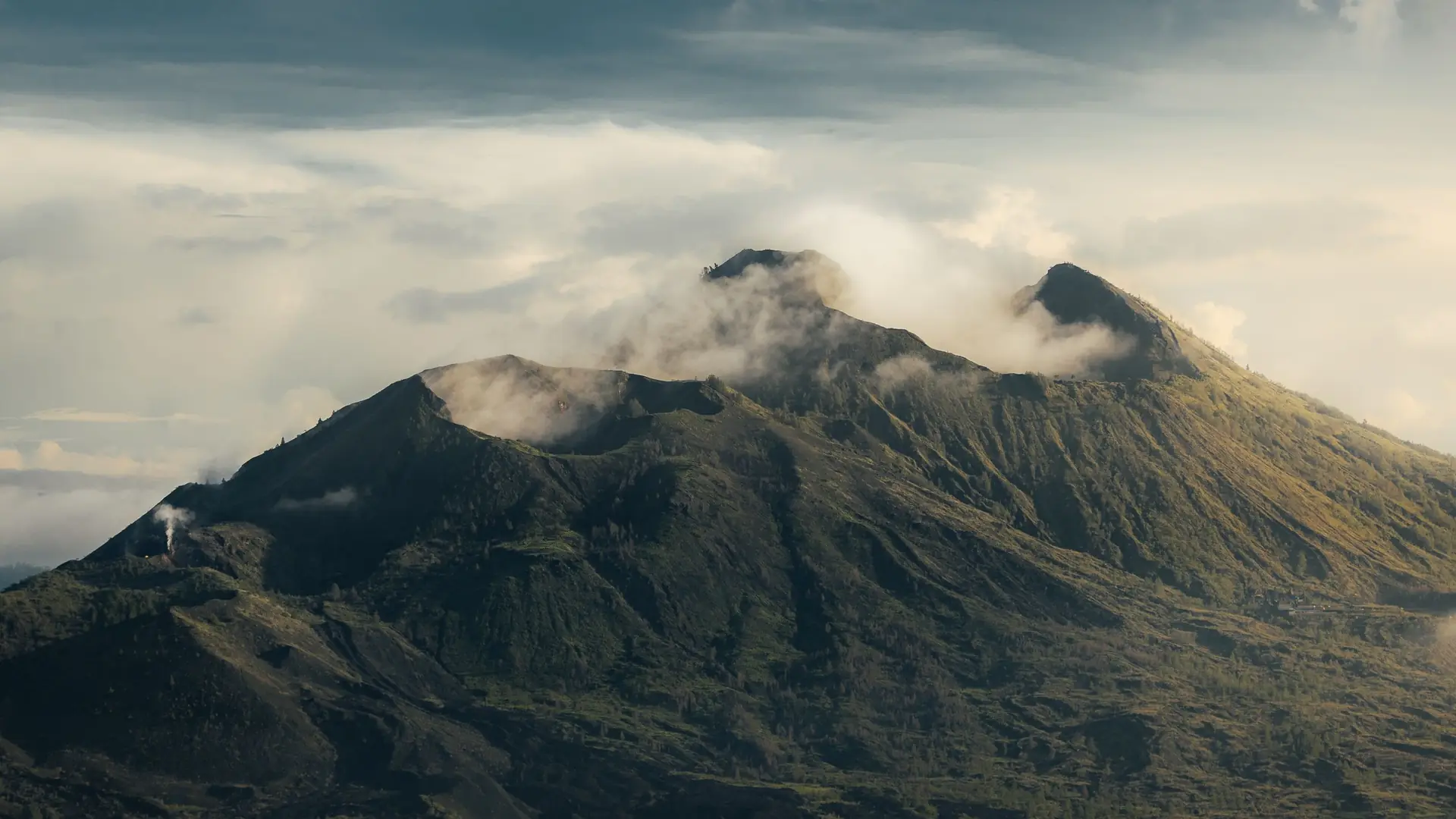 The summit of Mount Batur with cloud drifting over the crater