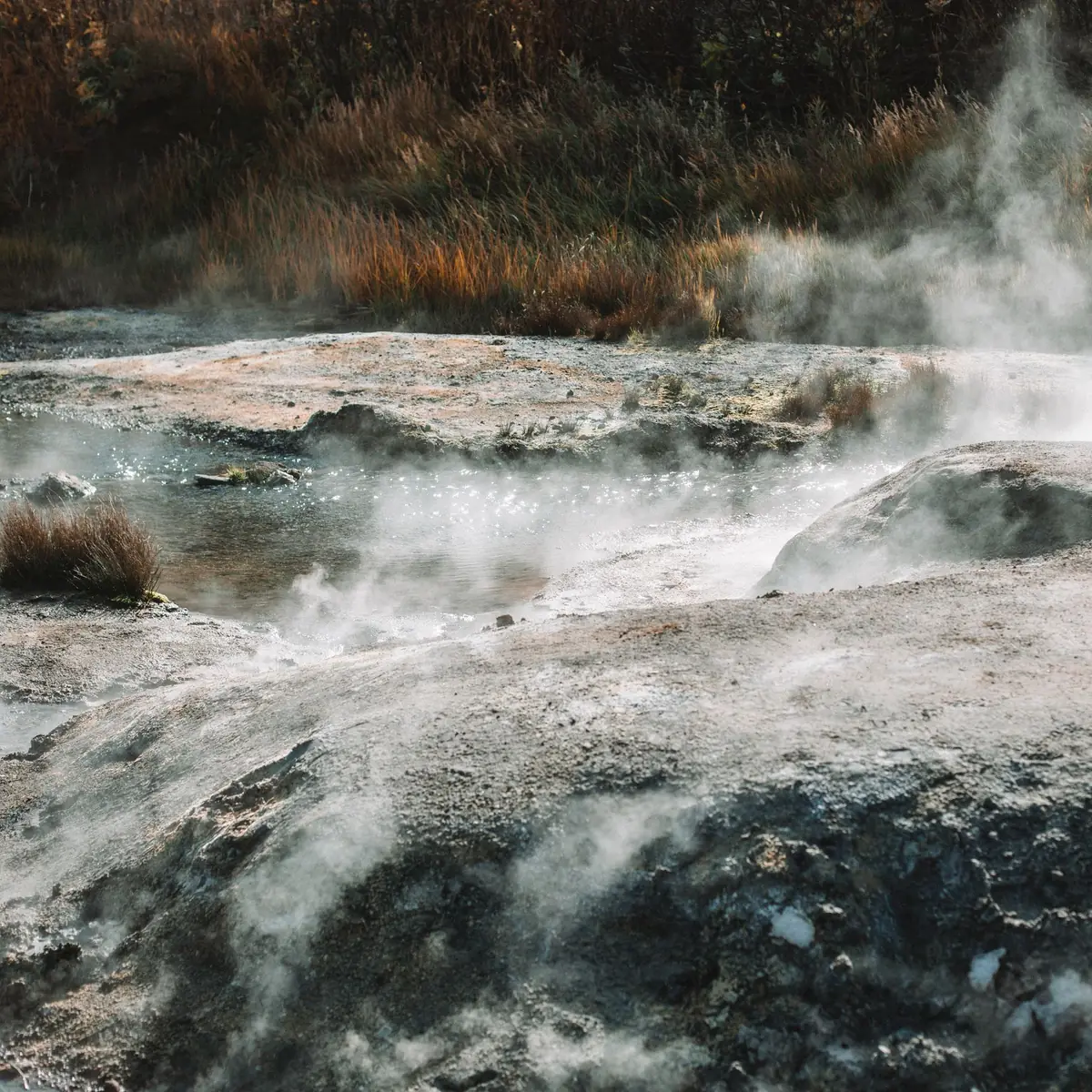 Steam rising from warm water running over pale stones