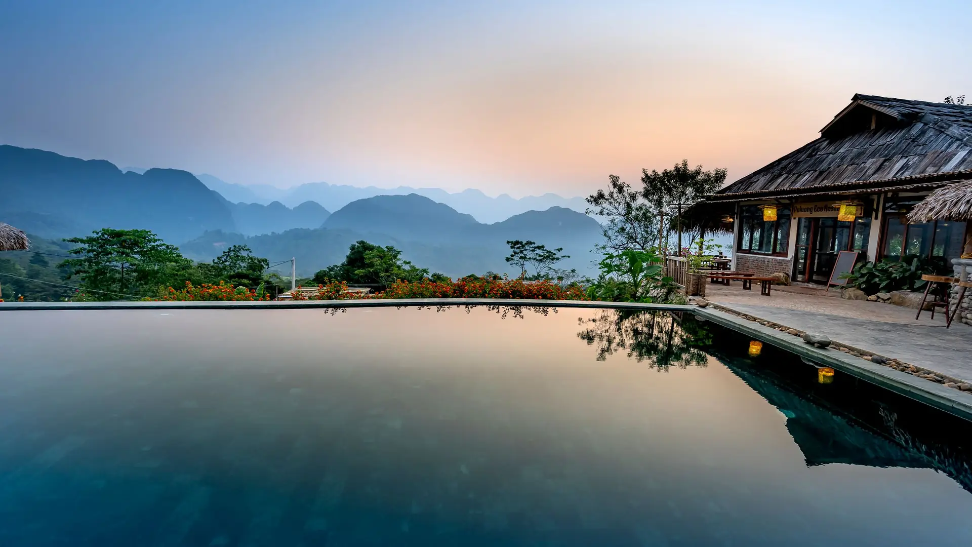 An outdoor pool at dusk with mountains on the horizon