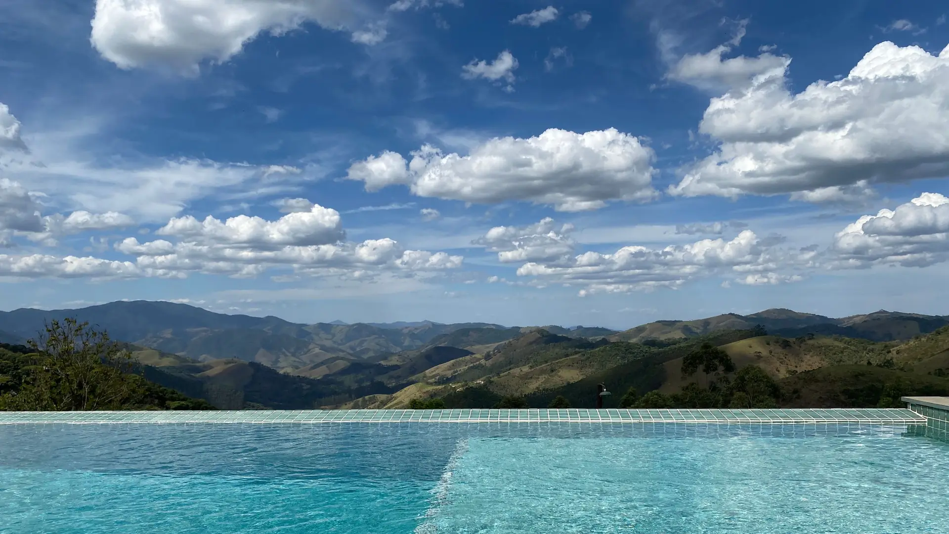 A swimming pool with a wide view of hills under a bright sky