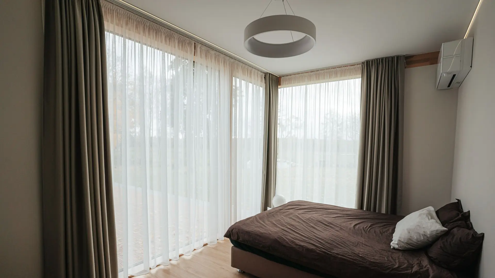 A calm bedroom with tall curtains and soft morning light